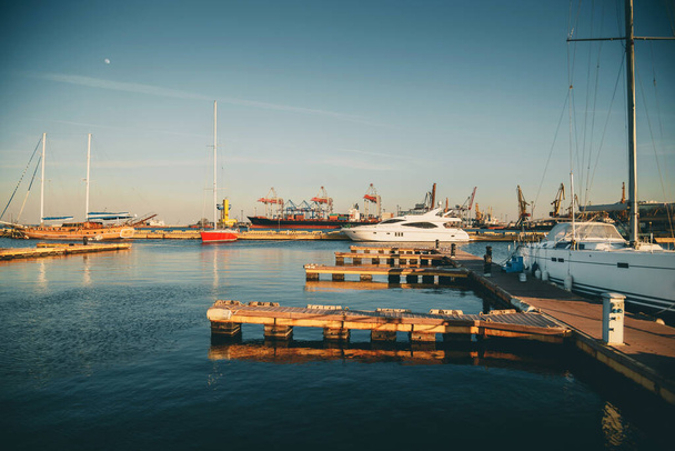 Beautiful port of Odessa, Black sea. Luxury yachts, ships and fishing boats standing in rows in harbor. Rich people traveling around the world. Sunny evening. - Valokuva, kuva