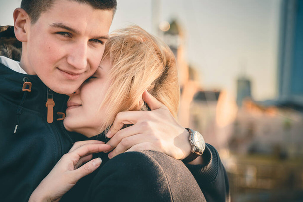 Close up of a cute young beautiful couple at sunset, man hugging his girlfriend softly, hipster, happy smiling outdoor portrait. - Foto, Imagen
