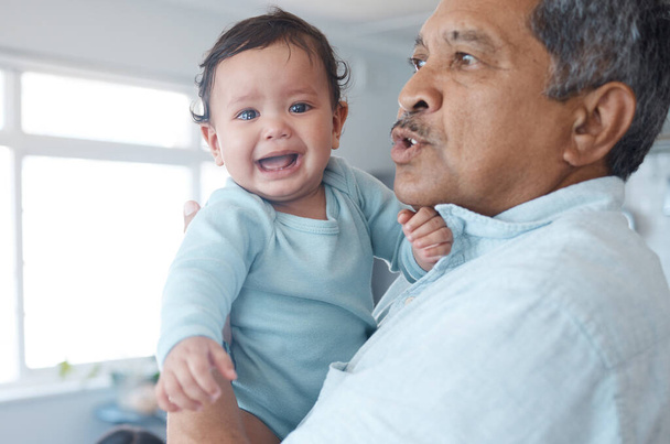 a mature man holding his crying grandchild at home. - Valokuva, kuva
