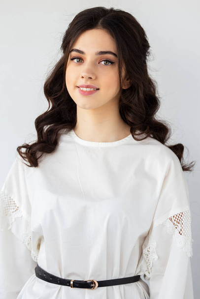 Güzel bir genç kadının ön portresi beyaz gömlek giyer, stüdyoda poz verir, izole beyaz arka plan. - Fotoğraf, Görsel