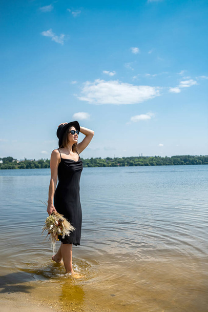 Ξυπόλητη γυναίκα με τα πόδια στη λίμνη σε μαύρο φόρεμα, μέρα του καλοκαιριού, τον τρόπο ζωής - Φωτογραφία, εικόνα