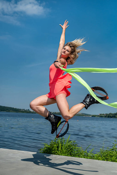  young pretty woman in kangoo jumping shoes doing exercise near city lake. Sports and health concept - Valokuva, kuva
