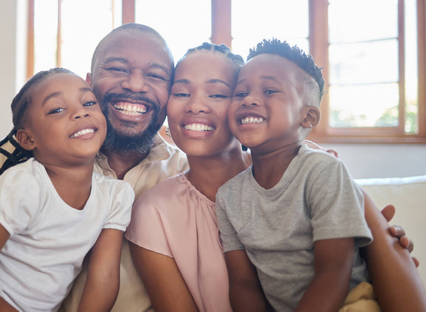 Egy fiatal afro-amerikai család portréja, akik együtt ülnek a kanapén és otthon mosolyognak.. - Fotó, kép