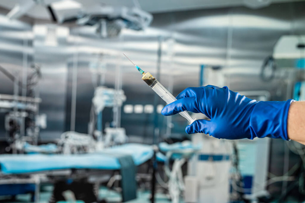 病院の外科事務所で手術の準備をするため液体の注射用プラスチック製のシリンジを持つ保護手袋を手にした男性 - 写真・画像