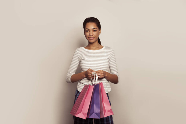 Happy young black woman with shopping bags against a white wall - Foto, Bild