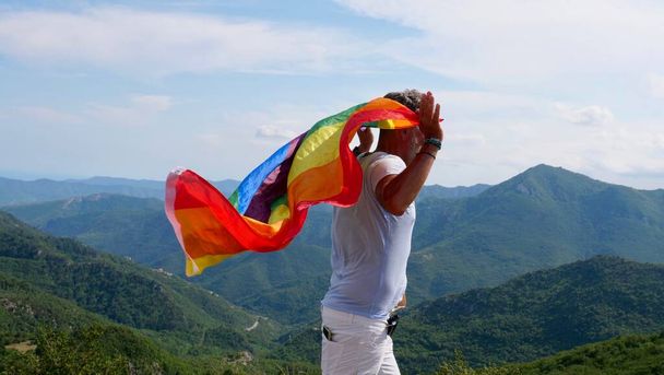 Bisexual, gay, old man, male, transsexual walk with LGBTQIA flag, rainbow peace in pride mounts on the nature on a day and celebrate Bisexuality Day or National Coming Out Day - Φωτογραφία, εικόνα