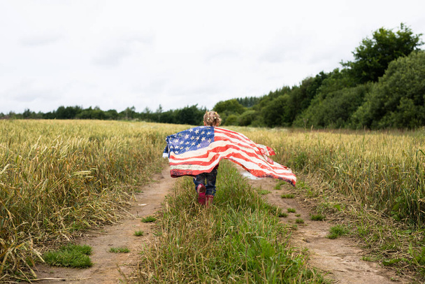 Little cute girl with american flag on the field - Фото, зображення