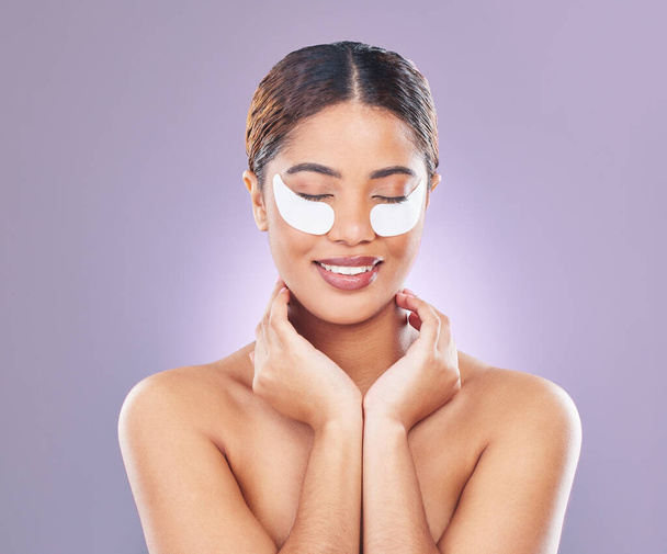Puffy eyes for who. a young woman using eye masks against a pink background - Photo, Image