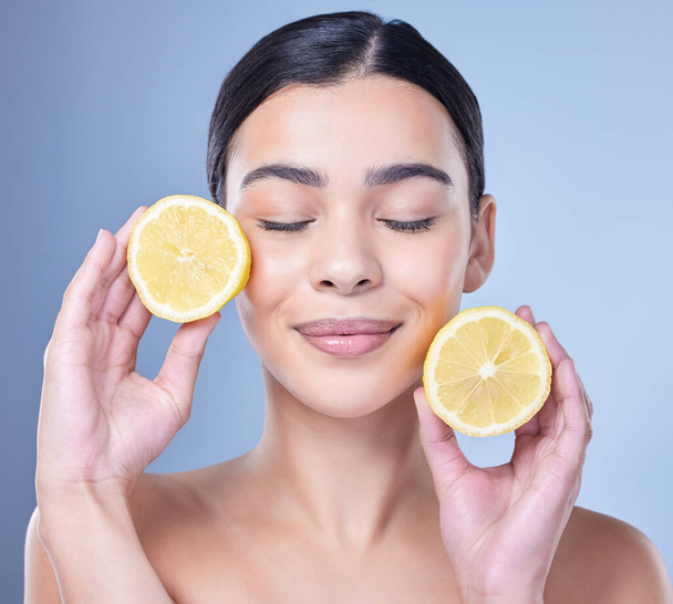 A happy smiling mixed race woman holding a lemon. Hispanic model promoting the skin benefits of a healthy diet against a blue copyspace background. - Φωτογραφία, εικόνα