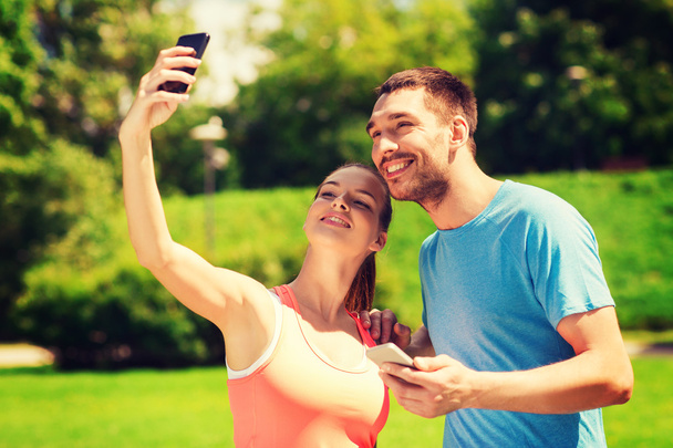 dwa uśmiechający się ludzie z zewnątrz smartfonów - Zdjęcie, obraz