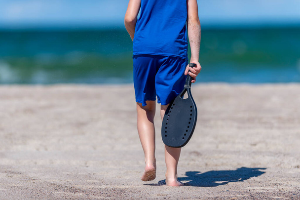 Мальчик играет в теннис на пляже. Детская спортивная концепция. Горизонтальный плакат спортивной тематики, поздравительные открытки, заголовки, веб-сайт и приложение - Фото, изображение