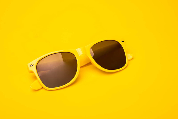 Yellow fancy, hipster sunglasses on a vibrant sunny background. Summertime, travel concept, banner, postcard with a copy space. - Photo, Image