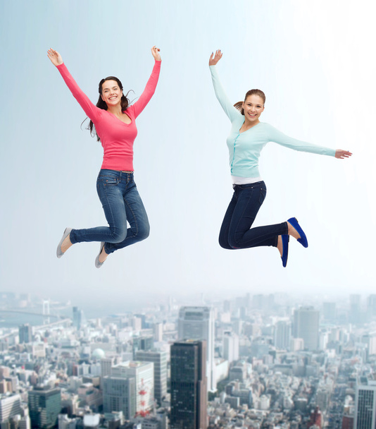 lachende jonge vrouwen springen in de lucht - Foto, afbeelding