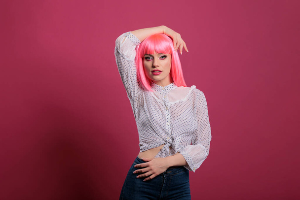 Portrait of pretty young adult with sexy makeup look and trendy style, feeling confident and attractive in front of studio camera. Glamour fashion icon with pink hairstyle and beautiful face. - Foto, Imagem