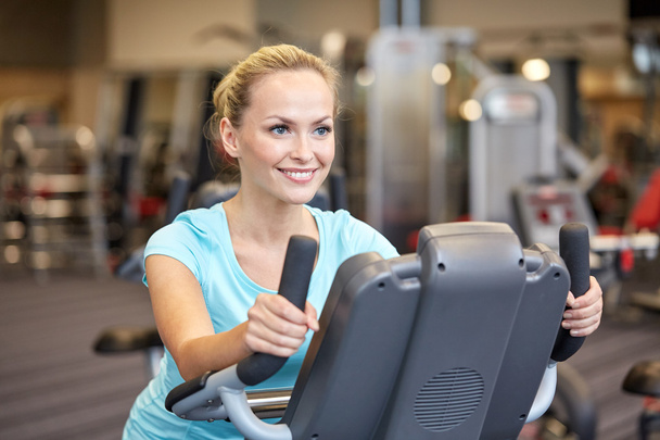 smiling woman exercising on exercise bike in gym - 写真・画像