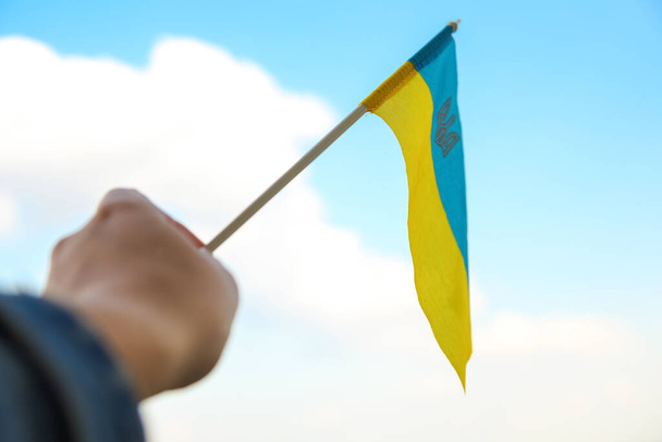 Defocus Ukraine flag. Large national symbol fluttering in blue sky. Support and help Ukraine, Independence Constitution Day, National holiday. Hand holding flag. Military. Closeup. Out of focus. - Zdjęcie, obraz