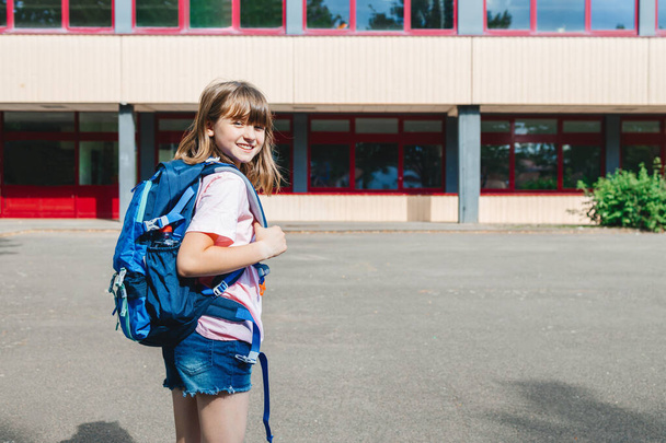 Portrait of a teenager schoolgirl in front of the school building. Children begin the school year. Back to school. - 写真・画像