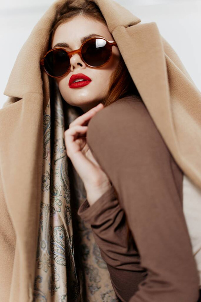 Une fille aux cheveux roux avec des lunettes et un manteau sur la tête pose en regardant ailleurs. Bannière pour la conception de mode d'un magasin de vêtements. Photo de haute qualité - Photo, image