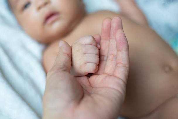 Dormir mano de bebé en la mano de papá de cerca en la cama, Nuevo concepto de familia - Foto, imagen