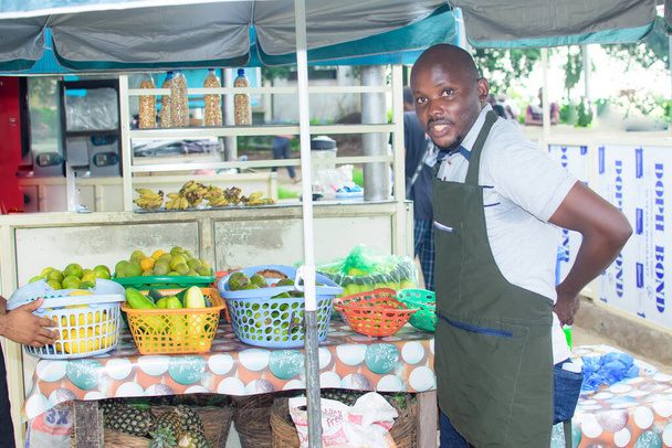 Un uomo africano drogheria e venditore di frutta legando il grembiule in preparazione per iniziare a vendere affari per il giorno - Foto, immagini