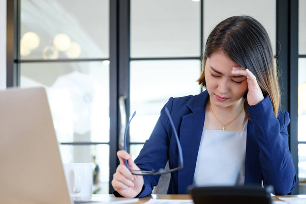 Asiatische Geschäftsfrau bedeckt ihr Gesicht mit beiden Händen vor dem Stress der Arbeit, frustriert über ihre Arbeit und außer Kontrolle. - Foto, Bild