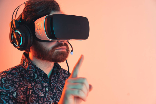 Close up shot of a stylish professional man wearingh the virtual reality headset and headphones using gesture operations on invisible menu. High quality photo - Fotografie, Obrázek