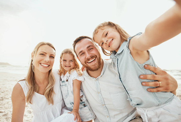 Portrait of happy caucasian family taking selfies while enjoying a fun summer vacation together at the beach. Loving parents bonding and creating special memories with their cute smiling daughters. - Fotoğraf, Görsel