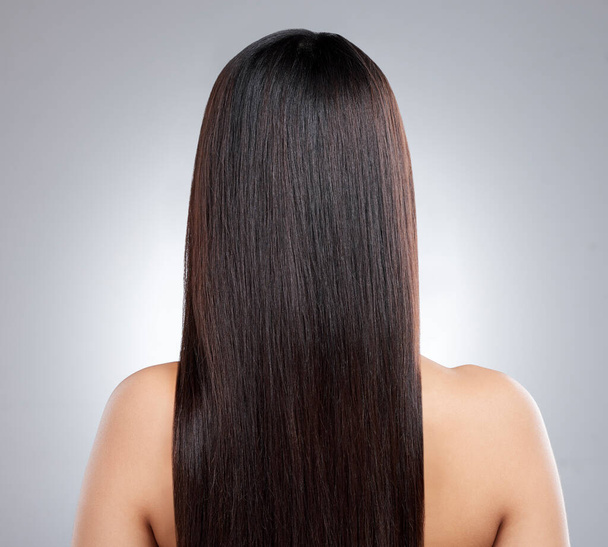 I love it all smooth and sleek. Rearview shot of a young woman with long silky hair posing against a grey background - Foto, immagini