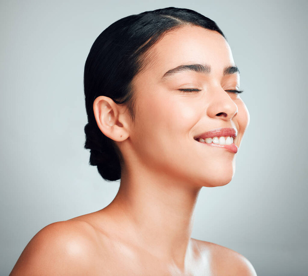 A beautiful young mixed race woman with glowing skin posing against grey copyspace background. Hispanic woman with natural glowing skin looking flirty and sexy in a studio. - Foto, immagini