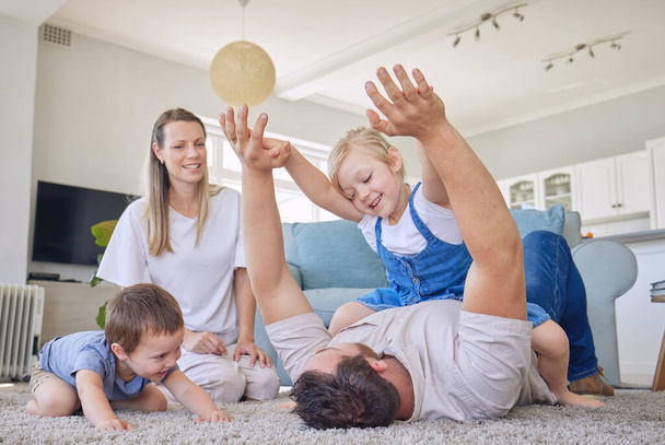 Family with daughter and baby son playing on the carpet in living room. Dad playing with his little girl and baby while mother sits by and watch them. Happy caucasian family bonding at home. - Fotografie, Obrázek