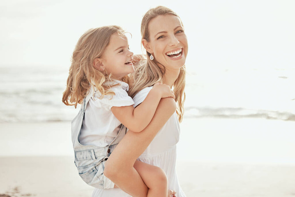 Fröhliche Mutter und Tochter amüsieren sich am Strand. Junge Mutter gibt ihrer Tochter Huckepackfahrt am Strand. Wertvolle Mutter-Tochter-Beziehung. - Foto, Bild