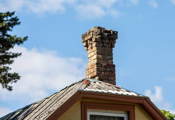 Old brick chimney on the edge of a roof. Heating and fire safety concept.. - Photo, Image