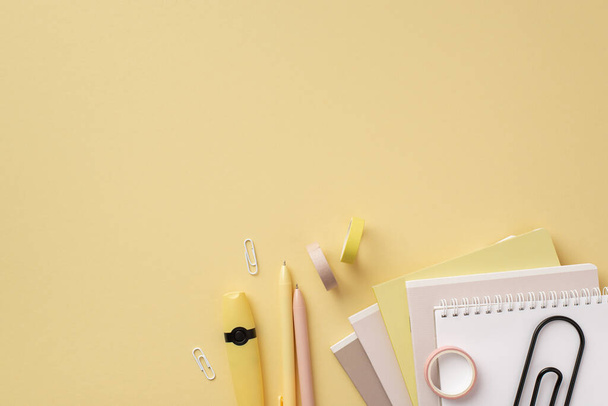 School supplies concept. Top view photo of stationery marker clips stack of copybooks adhesive tape and pens on isolated pastel yellow background with copyspace - Foto, imagen