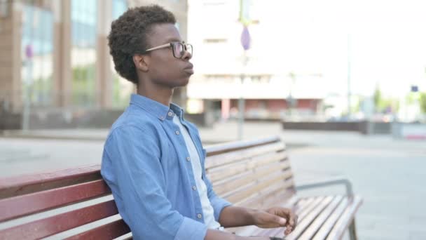 Afrikaanse man glimlachend naar de camera terwijl hij op de bank zit - Video