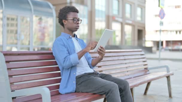Afrikaanse man viert Online Win op tablet tijdens het zitten buiten op de bank - Video