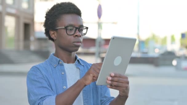 Африканський чоловік святкує онлайн-перемогу на планшеті на відкритому повітрі - Кадри, відео