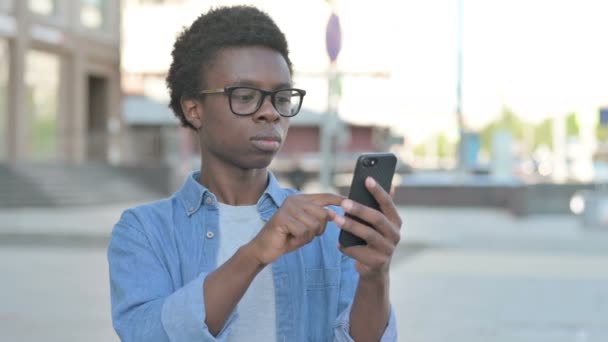 African Man Celebrating Online Success on Smartphone Outdoor - Metraje, vídeo