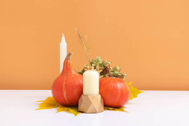 Autumn creative composition. Dried leaves wreath, pumpkins and candle on white orange background. Autumn fall and thanksgiving day concept. Still life. - Foto, immagini