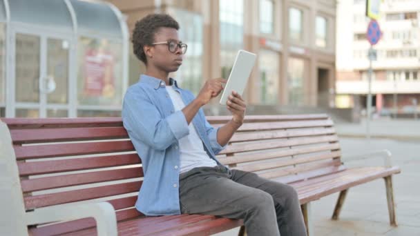 Online video Chat op tablet door Afrikaanse man zitten buiten op de bank  - Video