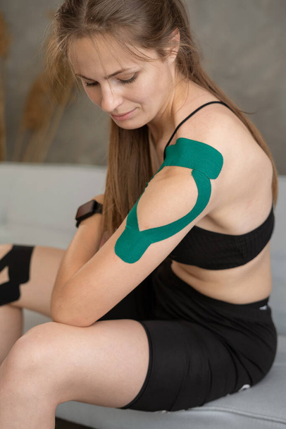 Shoulder treatment with kinesio tape. Kinesiology taping treatment with green tape on athlete patient injured arm. - Foto, afbeelding