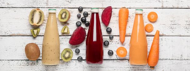 Bottles of healthy smoothies and ingredients on light wooden background - Photo, Image