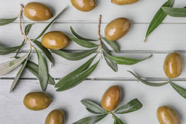 Composition with tasty green olives on light wooden background - Photo, image