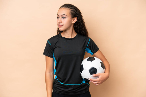 Young football player woman isolated on beige background looking to the side - Zdjęcie, obraz