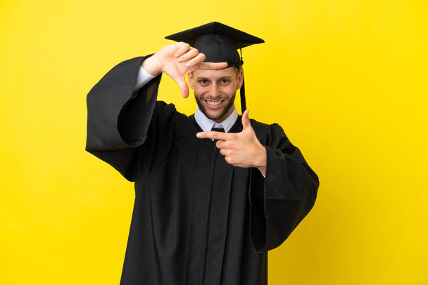 Nuori yliopistosta valmistunut valkoihoinen mies eristetty keltaisella taustalla keskittyen kasvot. Kehyssymboli - Valokuva, kuva