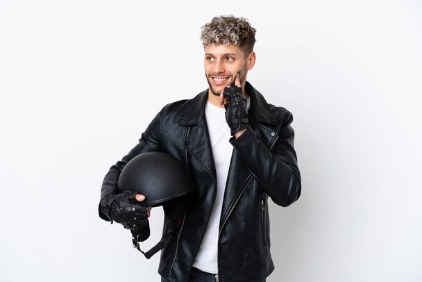 Молодий чоловік з мотоциклетним шоломом ізольований на білому тлі думаючи про ідею під час пошуку
 - Фото, зображення