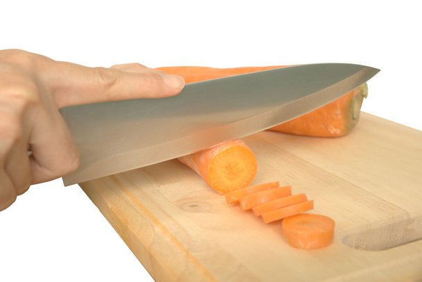 Woman hand slicing carot on wooden chopping block - Zdjęcie, obraz