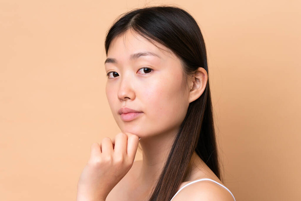 Young Chinese woman isolated on beige background . Portrait - 写真・画像