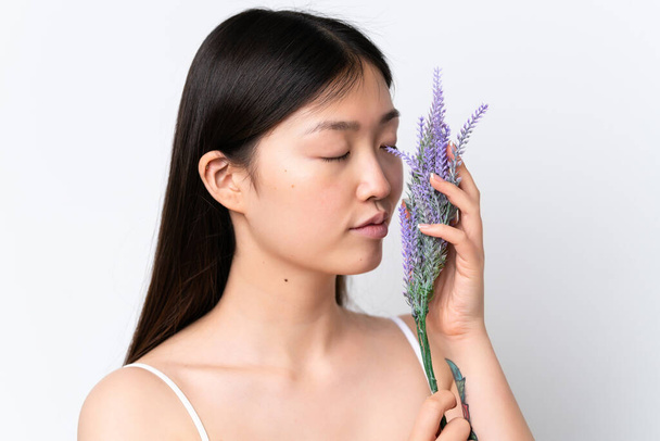 Junge Chinesin isoliert auf weißem Hintergrund mit einer Lavendelpflanze. Porträt aus nächster Nähe - Foto, Bild