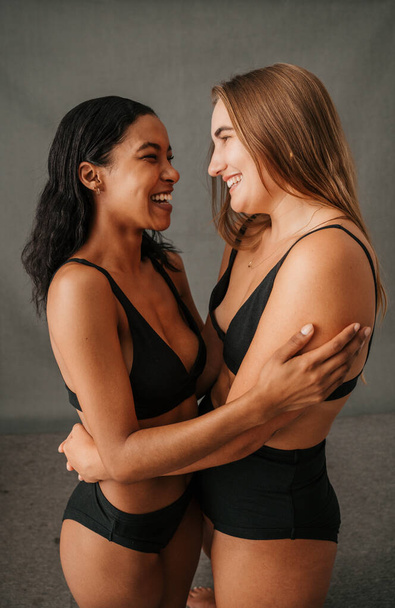 Two very happy smiling girlfriends in the studio embracing in there underwear. High quality photo - Foto, imagen
