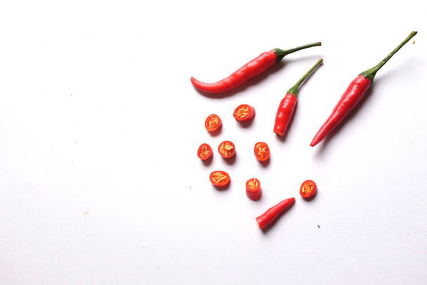kopieer ruimte een rijpe rode hete chili pepers gesneden in stukken groenten geïsoleerd op witte achtergrond.koken ingrediënten - Foto, afbeelding